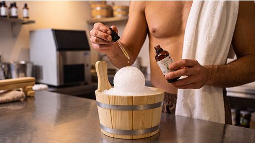 Sauna master pouring essential oil on ice balls